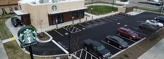 A parking lot filled with various cars, featuring a drive-thru area nearby. The scene is set in an urban environment with clear road markings and buildings visible in the background.