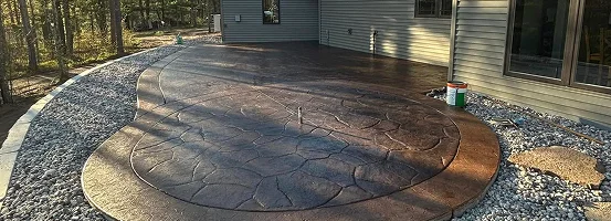 A large circular object placed on the ground outside, surrounded by a tree and situated on a patio.