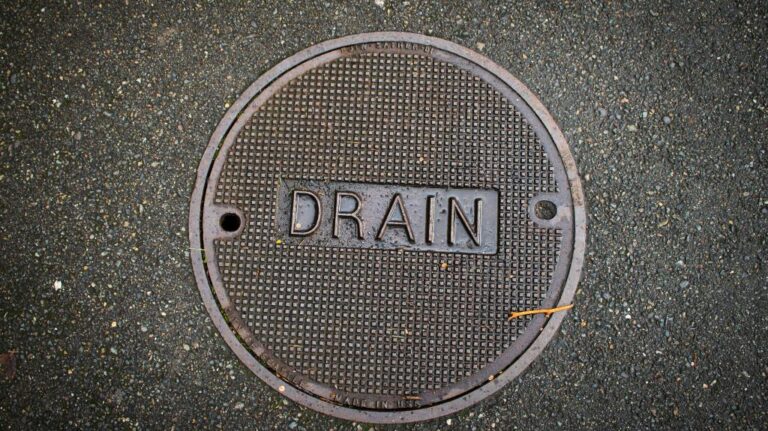 round metal manhole cover, clearly labeled with the word "DRAIN"