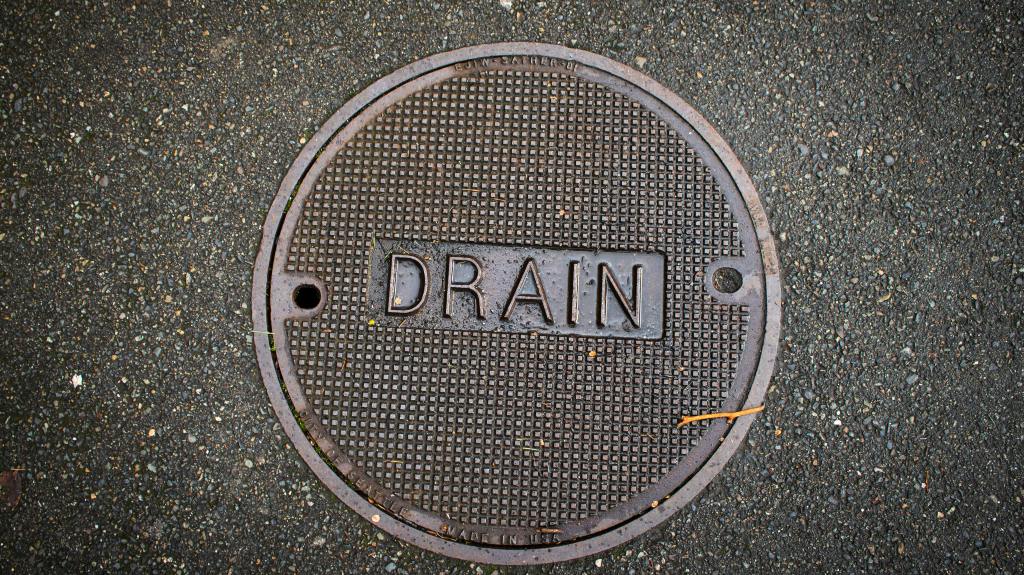 round metal manhole cover, clearly labeled with the word "DRAIN"