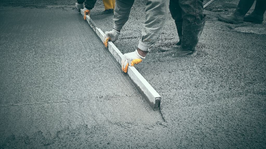 Construction worker uses trowel to level cement mortar screed