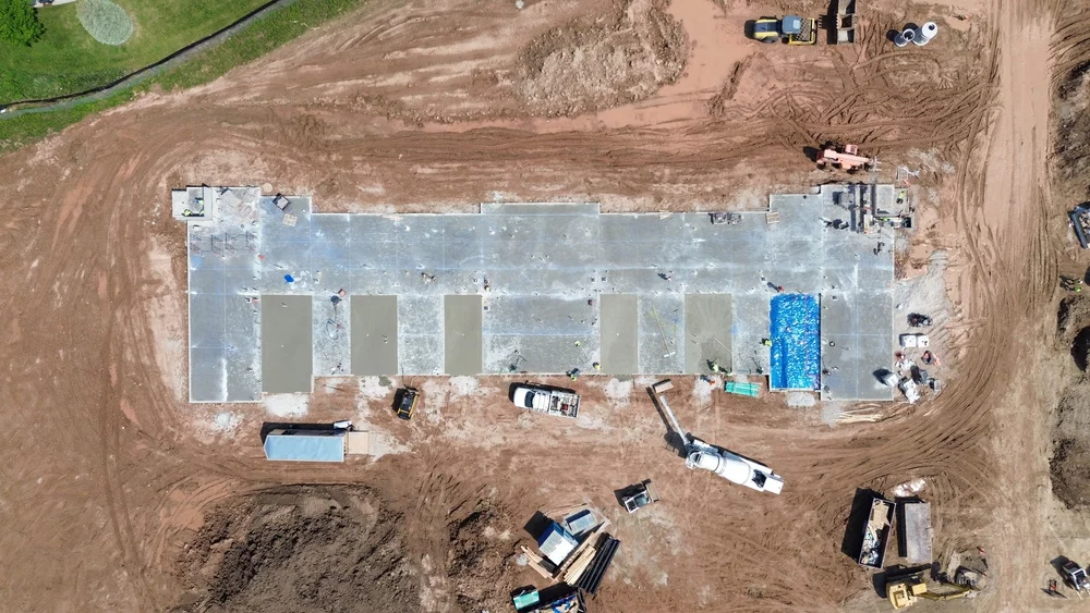 Aerial view of a construction site featuring a partially built structure surrounded by construction equipment and materials