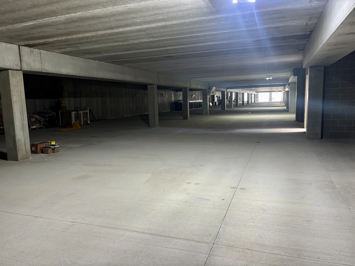 A spacious, empty parking garage featuring smooth concrete floors and no vehicles present