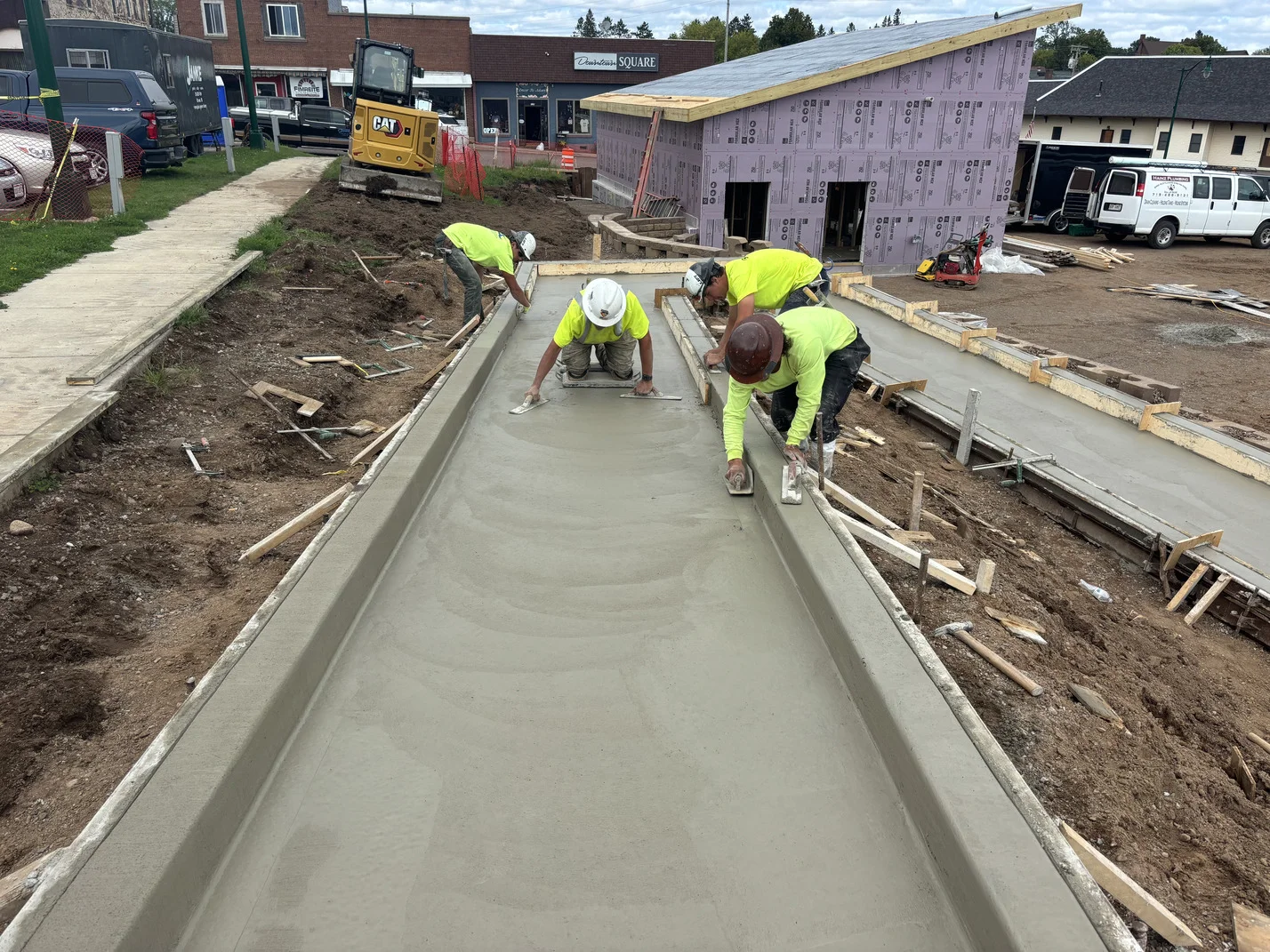 Construction workers pouring concrete on a slab, wearing safety gear and focused on their task