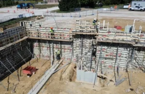 Construction site with workers assembling concrete formwork and steel reinforcements.