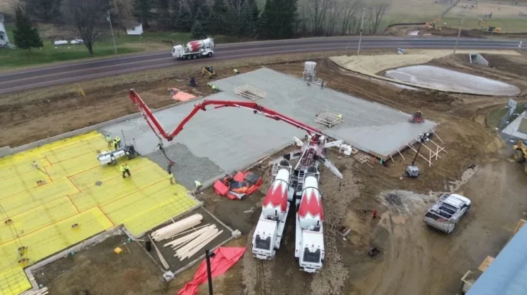 Aerial view of construction site with concrete pouring, workers, mixers, and equipment.