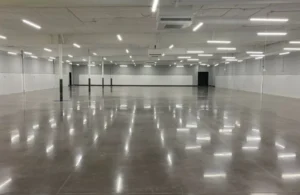 Spacious, empty industrial room with polished concrete floor and white walls.