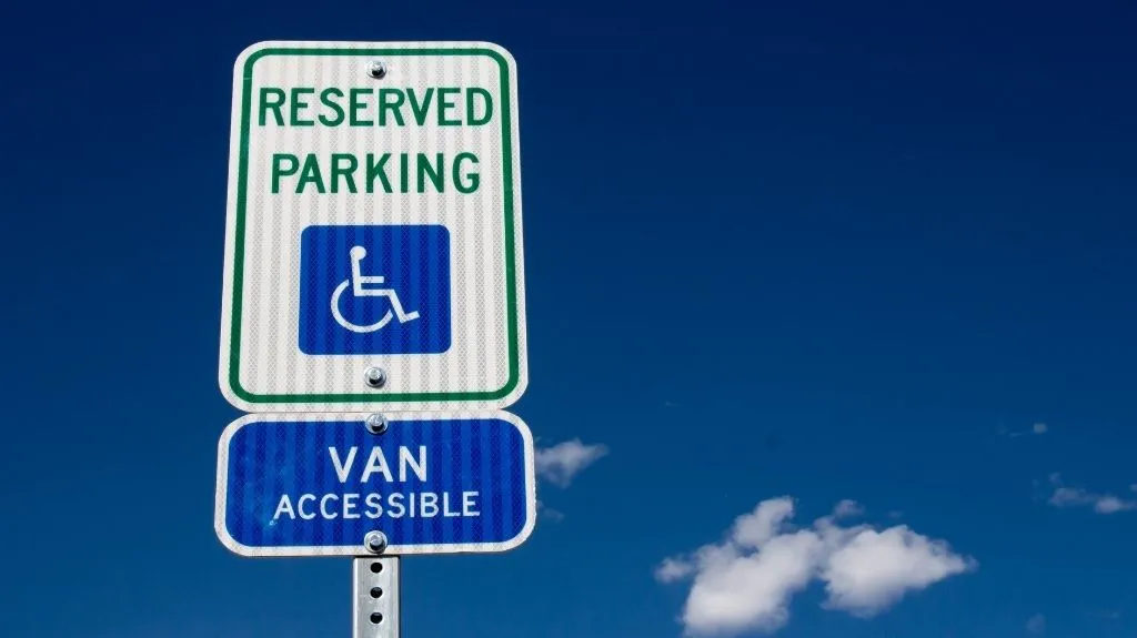 Reserved parking sign for van accessible handicapped space against clear blue sky.
