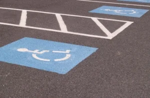 Blue handicap parking symbols painted on black asphalt with white striped lines.