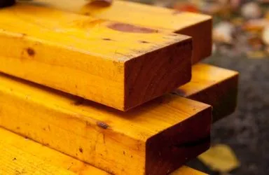 Stack of smooth, yellow-painted wooden planks with natural grain and knots.